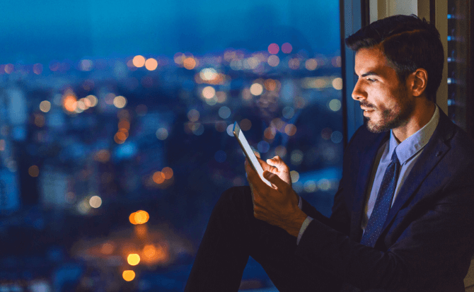 A man in a dark suit looking at his smartphone.