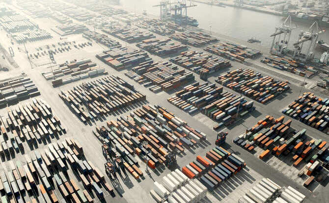 An aerial view of a large port filled with countless rectangular shipping containers stacked high