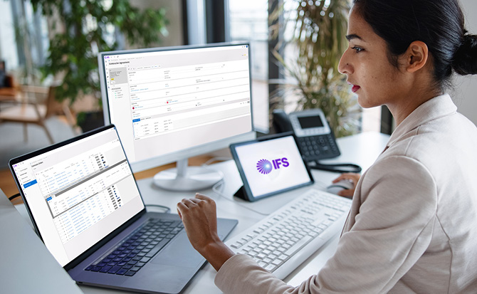 Business professional using IFS Cloud Service Management platform on multiple devices in office setting