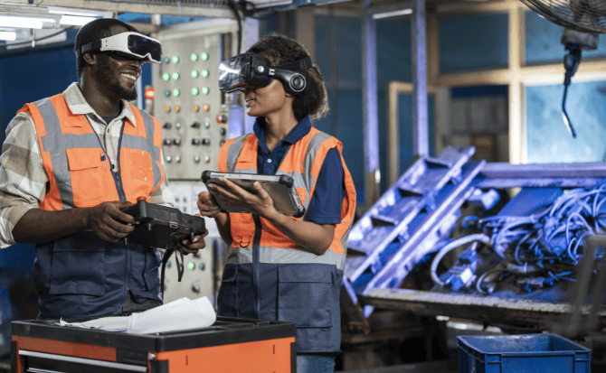 Two industrial workers are using VR and augmented reality technology to control machinery. One worker holds a controller, while the other uses a tablet.