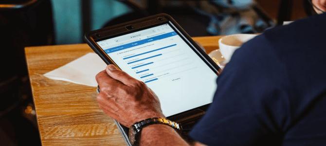 A person's hands holding a tablet, showing a list of links or search results on the screen.