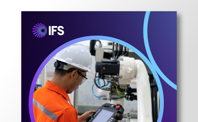 A male engineer in an orange jumpsuit and white hard hat operates a control panel near a robotic arm