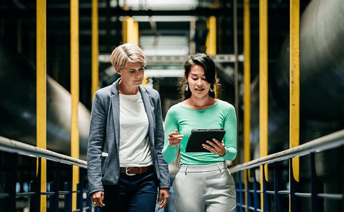 Two people looking at a tablet in an industrial setting