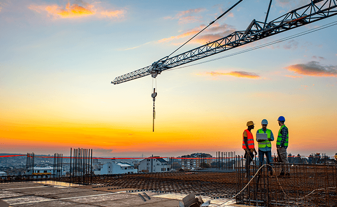 Construction site with a tower crane and three workers.