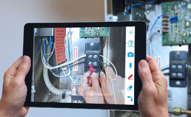 Una persona utilizza un tablet per ricevere Remote assistance, con istruzioni in realtà aumentata sovrapposte che guidano il processo di riparazione di un macchinario.