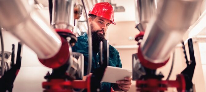 Man using Asset Lifecycle Management software on a laptop in a factory