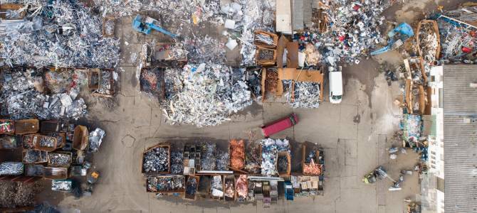 Aerial view of a recycling facility showcasing various sorted scrap materials, vehicles, and workers, emphasizing the concept of Circular Economy