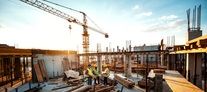 Construction workers on a building site discussing plans, illustrating what the construction industry involves in terms of teamwork and infrastructure development.