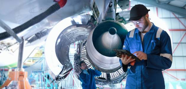 Two technicians working on an aircraft engine in a high-tech defense manufacturing facility, showcasing the skilled workforce behind military-grade technology.