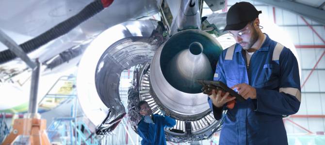 Uomo accanto al motore di un aereo che utilizza il software Service Lifecycle Management su un tablet