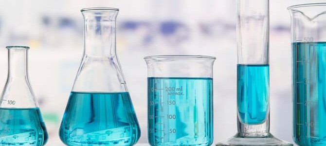 Various laboratory glassware containing blue liquid, including a conical flask, an Erlenmeyer flask, a beaker, and a graduated cylinder.