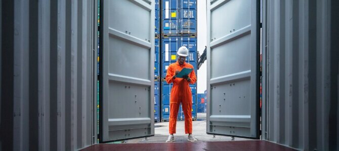 Worker in shipping container inspecting documents, symbolizing Supply Chain Risk Management.