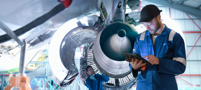 Technicians inspecting an aircraft engine using a tablet powered by MRO software for real-time maintenance and repair operations.