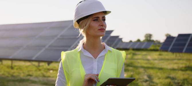 Woman with tablet near solar panels, using CSRD software for sustainability reporting.