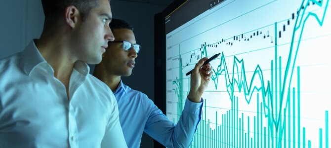 Two professionals analyze data trends on a digital screen as part of an Asset Investment Planning strategy.